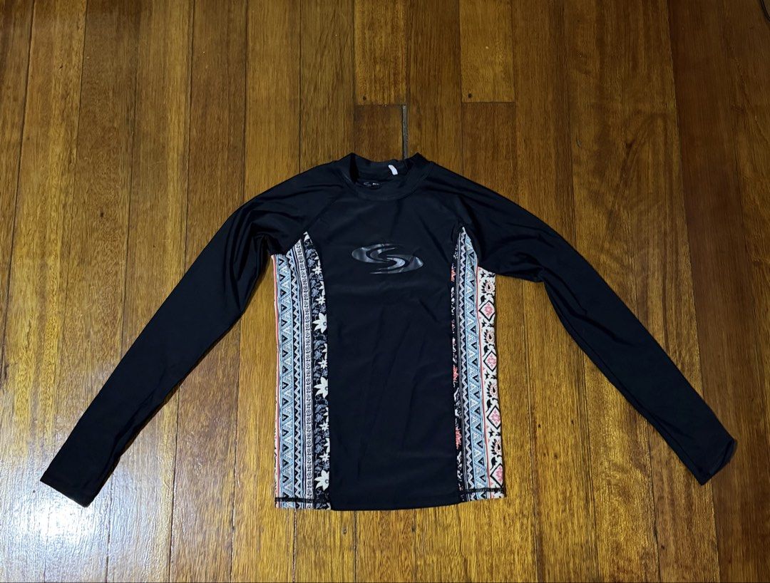 Sun N Sand Long Sleeve Rash Guard (Category: Rash guard) located in Paranaque City. Submitted by declutternsell.729 (Listing ID 1463776059, Image 1). Description: - Brand: Sun N Sand - Color: Black - Style: Long sleeve rash guard - Design: Tribal-inspired patterned panels on sides - Use: Ideal for swimming and sun protection - Care Instructions: Hand wash only - Important Note: Do not iron on rubberized print.