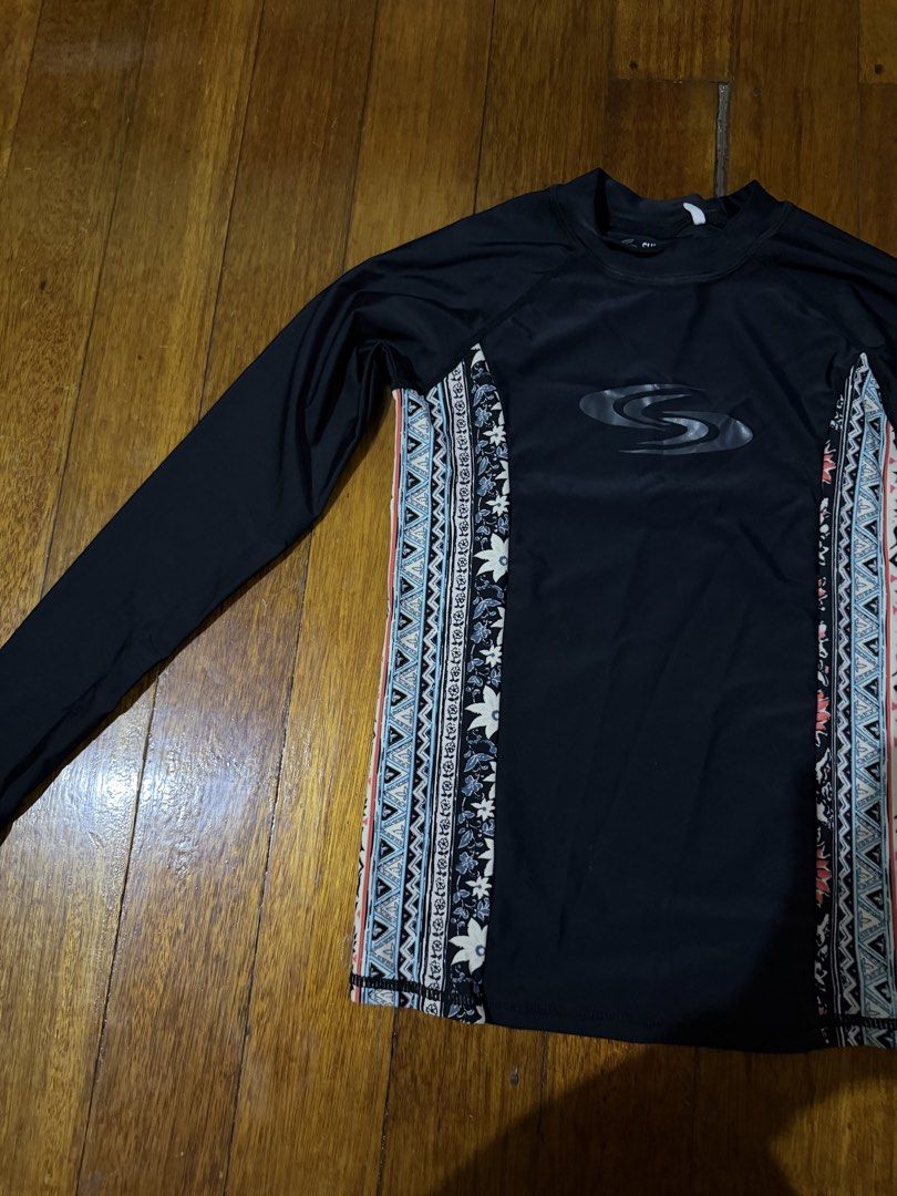 Sun N Sand Long Sleeve Rash Guard (Category: Rash guard) located in Paranaque City. Submitted by declutternsell.729 (Listing ID 1463776059, Image 2). Description: - Brand: Sun N Sand - Color: Black - Style: Long sleeve rash guard - Design: Tribal-inspired patterned panels on sides - Use: Ideal for swimming and sun protection - Care Instructions: Hand wash only - Important Note: Do not iron on rubberized print.