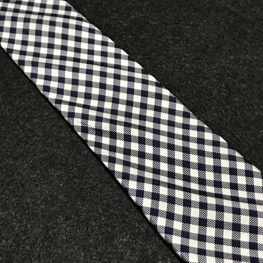 Tommy Hilfiger NWT Gingham Neck Tie (Category: Ties) located in Taguig. Submitted by retrogaze (Listing ID 1463797816, Image 3). Description: This 100% silk necktie by Tommy Hilfiger features a crisp white base woven with a smooth, refined twill finish. The body displays a classic, small-scale gingham grid pattern in dark navy blue and pure white, bringing timeless Ivy League preppy style to a sharp silhouette. Recommended Suit & Shirt Pairings: 