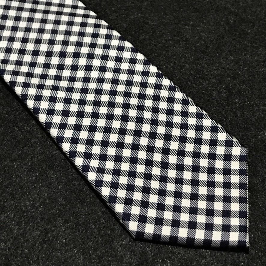 Tommy Hilfiger NWT Gingham Neck Tie (Category: Ties) located in Taguig. Submitted by retrogaze (Listing ID 1463797816, Image 2). Description: This 100% silk necktie by Tommy Hilfiger features a crisp white base woven with a smooth, refined twill finish. The body displays a classic, small-scale gingham grid pattern in dark navy blue and pure white, bringing timeless Ivy League preppy style to a sharp silhouette. Recommended Suit & Shirt Pairings: 