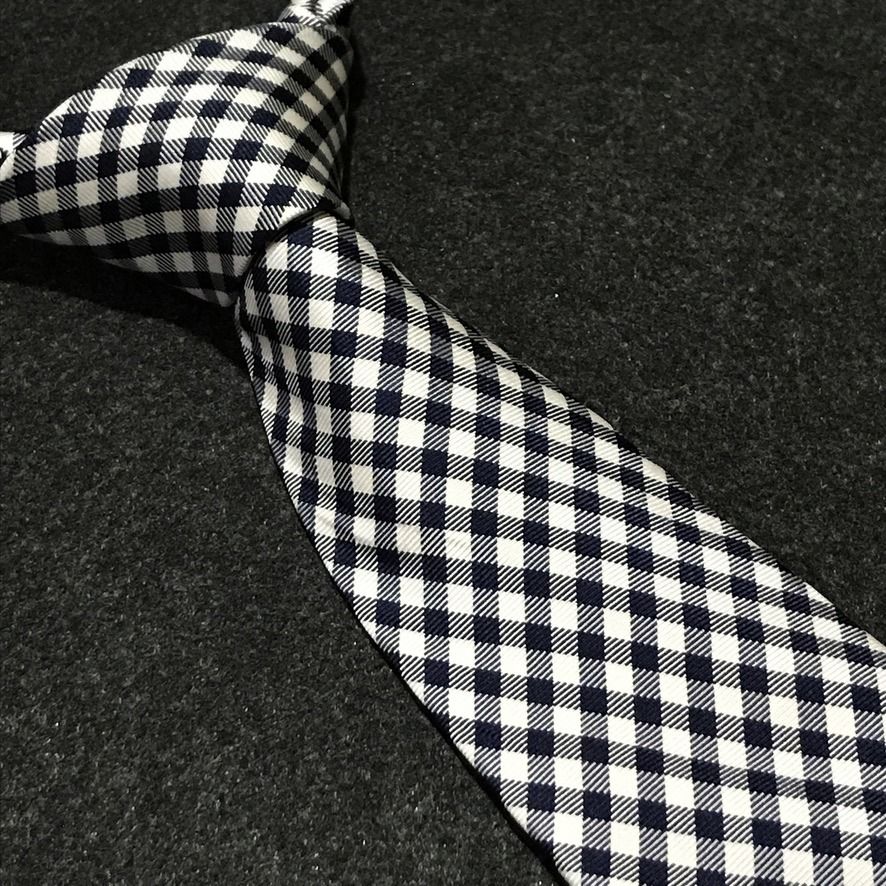 Tommy Hilfiger NWT Gingham Neck Tie (Category: Ties) located in Taguig. Submitted by retrogaze (Listing ID 1463797816, Image 1). Description: This 100% silk necktie by Tommy Hilfiger features a crisp white base woven with a smooth, refined twill finish. The body displays a classic, small-scale gingham grid pattern in dark navy blue and pure white, bringing timeless Ivy League preppy style to a sharp silhouette. Recommended Suit & Shirt Pairings: 