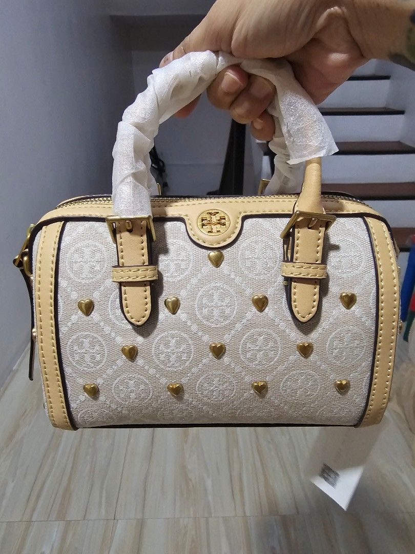 Tory Burch Monogram Lasercut Bucketbag (Category: Shoulder Bags) located in Quezon City. Submitted by Diaholics_Jewelry (Listing ID 1463889344, Image 3). Description: - Cute Tory Burch barrel bag - Beige and cream monogram print - Gold heart details - Tan leather trim and handles - Detachable crossbody strap included - Small protective feet on the bottom - Ideal for everyday use or a night out.