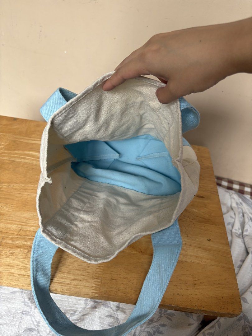 Trader Joe's Canvas Tote Bag Small (Category: Tote Bags) located in Imus. Submitted by kyla_declutters (Listing ID 1463775036, Image 2). Description: - Cute canvas tote bag from Trader Joe's - Cream colored with light blue accents - Features a convenient front pocket - Interior is lined with light blue fabric - Ideal for groceries, shopping, or everyday use - Easy and comfortable to carry.