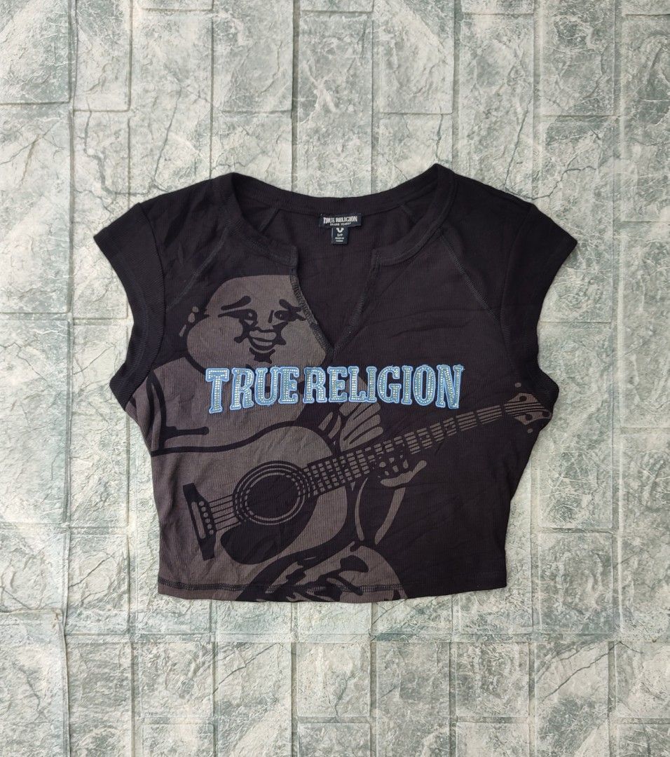 True Religion Crystal Buddha Notch Tee (Category: Sleeveless) located in Bayambang. Submitted by mon10192816 (Listing ID 1463751779, Image 2). Description: - Width 17 - Length 16 - True Religion cropped t-shirt - Features a Buddha and guitar graphic - Rhinestone details on 'True Religion' text - Notch neckline - Short sleeves - Material: Polyester, Rayon, Spandex blend - Perfect for a casual, edgy style.