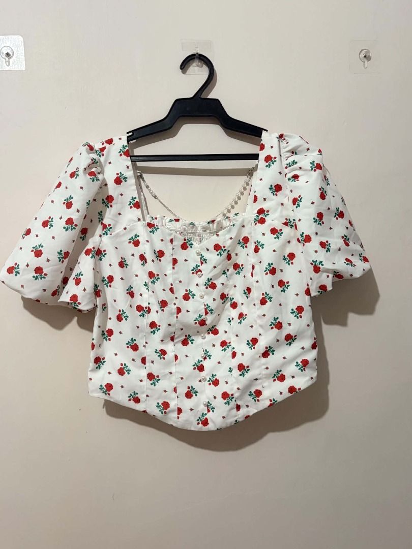 White Rose Print Puff Sleeve Square Neck Top (Category: Blouses) located in San Leonardo. Submitted by burgossanleonardo.12345 (Listing ID 1463868258, Image 1). Description: - Adorable white cropped top - Features a charming red rose print - Stylish puff sleeves - Elegant square neckline - Flattering smocked detail on the front bodice - Functional button details down the front - Perfect for pairing with high-waisted jeans or skirts.