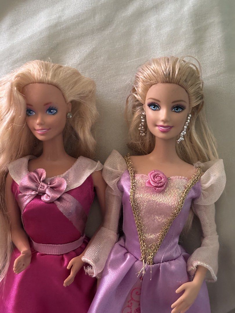 2 Barbie Dolls Princess Dresses (Category: Kids Toys) located in La Trinidad. Submitted by caicai1926 (Listing ID 1464013927, Image 2). Description: - Two beautiful Barbie princess dolls - Both have blonde hair and blue eyes - Doll 1: Pink princess gown with bow detail - Doll 2: Purple and pink satin gown with gold trim and rose accent - Includes matching shoes for both dolls.