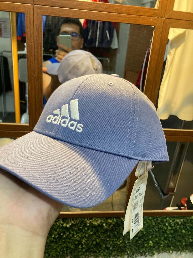 Adidas BBALL CAP COT Purple Baseball Cap OSFM (Category: Caps & Hats) located in Trece Martires City. Submitted by djaothriftshop (Listing ID 1463972697, Image 1). Description: - Brand new Adidas cap in a lovely light purple shade. - Iconic Adidas logo prominently displayed on the front. - Adjustable strap at the back ensures a perfect, comfortable fit. - Original tag still attached, showing the original price. - Ideal for adding a stylish touch 