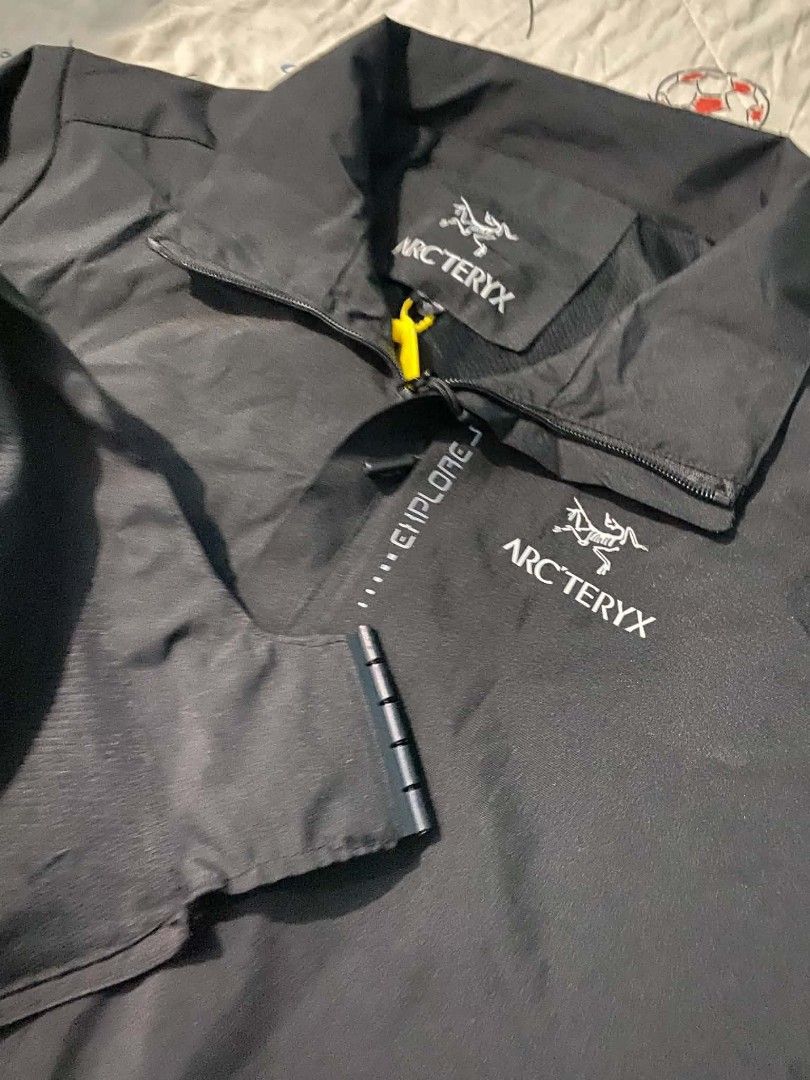 Arc'teryx Black Anorak Jacket with Hood (Category: Coats, Jackets and Outerwear) located in Manila. Submitted by jerms.thriftah (Listing ID 1463972295, Image 3). Description: - Black Arc'teryx anorak jacket - Stowable hood - Reflective "EXPLORE" text and dots on front - Zippered side pockets - Elastic cuffs and hem - Ideal for outdoor activities.