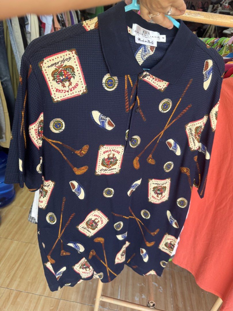 Balenciaga 100% Original (Category: Luxury Apparel) located in Manila. Submitted by wildbear.e10374 (Listing ID 1463958602, Image 3). Description: - Navy blue Balenciaga Paris polo shirt - Features a fun all-over print with golf motifs, clubs, and 'Open Club' graphics - Short sleeves and collared neckline - Made in Italy - Ideal for Occasion or daily Balenciaga collectors.