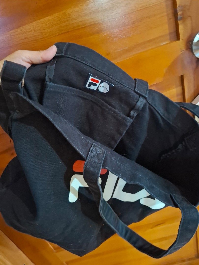 Black Fila Tote Bag (Category: Tote Bags) located in Muntinlupa City. Submitted by googoosh_collection (Listing ID 1463971957, Image 3). Description: - Classic black Fila tote bag - Features iconic Fila logo on the front - Made from durable canvas material - Two comfortable shoulder straps - Ideal for everyday use, shopping, or carrying essentials - Simple and stylish design *RFS: Decluttering (Need lang po labhan na stock sa package from abroad.