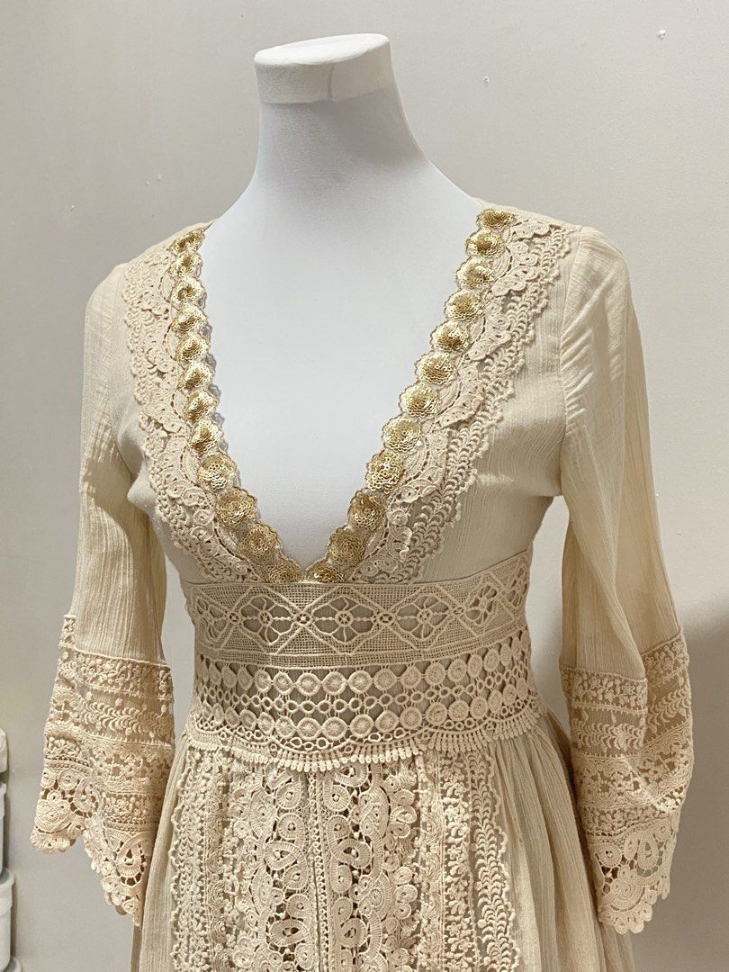 Boho Lace Mini Dress (Category: Dresses) located in Manila. Submitted by toastybread (Listing ID 1464024045, Image 3). Description: - Cream/beige mini dress - Intricate lace detailing - Deep V-neck with gold bead accents - Bell sleeves - Cinched waist with crochet trim - Back zipper closure - Perfect for a bohemian or festival look.