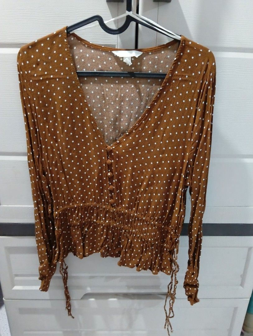 Brown Polka Dot Long Sleeve Blouse (Category: Blouses) located in Las Pinas. Submitted by _jmpulsivebuyerxx (Listing ID 1464023710, Image 1). Description: - Adorable brown blouse with classic white polka dots. - Flattering V-neckline with functional button details. - Smocked waist for a comfortable, defined silhouette. - Adjustable tie at the hem for a customized fit. - Long sleeves with elastic cuffs for easy wear. - Perfect for both casual outi