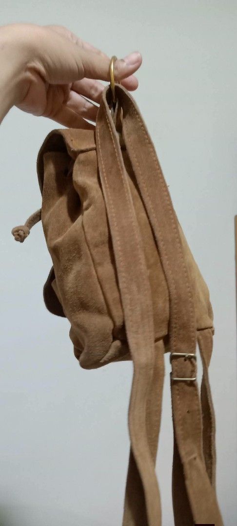 Brown Suede Mini Backpack with Front Pocket (Category: Backpacks) located in Gapan. Submitted by montesnora80204 (Listing ID 1464073228, Image 3). Description: - Adorable brown suede backpack - Convenient front pocket with snap closure - Secure main compartment with clasp and drawstring - Adjustable straps for comfortable wear - Ideal for carrying your daily essentials - Features a unique vintage style.