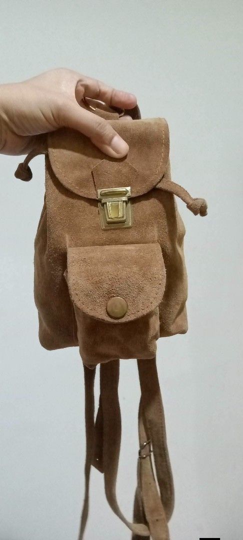 Brown Suede Mini Backpack with Front Pocket (Category: Backpacks) located in Gapan. Submitted by montesnora80204 (Listing ID 1464073228, Image 1). Description: - Adorable brown suede backpack - Convenient front pocket with snap closure - Secure main compartment with clasp and drawstring - Adjustable straps for comfortable wear - Ideal for carrying your daily essentials - Features a unique vintage style.