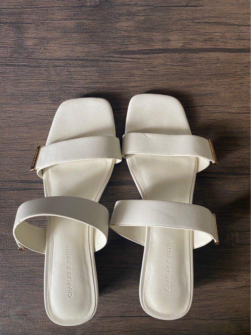 Charles & Keith White Double Strap Slide Sandals (Category: Flats & Sandals) located in Quezon City. Submitted by jiujitsu_la (Listing ID 1463964739, Image 1). Description: - Brand: Charles & Keith - Color: White - Style: Slide Sandals - Features: Double strap design, subtle gold accent - Toe Shape: Square toe - Closure: Slip-on - Occasion: Casual wear, versatile for dressing up.