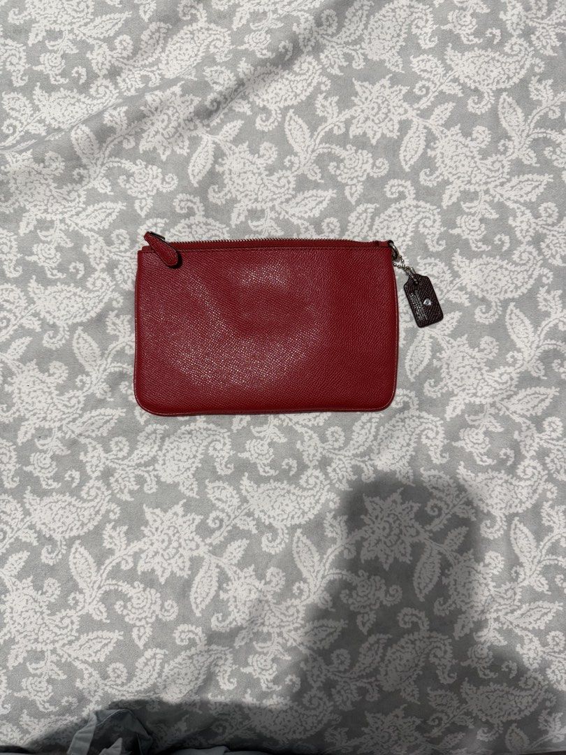 Coach Red Leather Pouch with Emblem (Category: Purses & Pouches) located in Quezon City. Submitted by akestrella (Listing ID 1464080971, Image 2). Description: - Authentic Coach red leather pouch - Features a cool emblem on the front - Secure zipper closure - Interior has a small Coach tag - Ideal for organizing your essentials - Approximate dimensions: 8 inches wide x 4 inches tall.