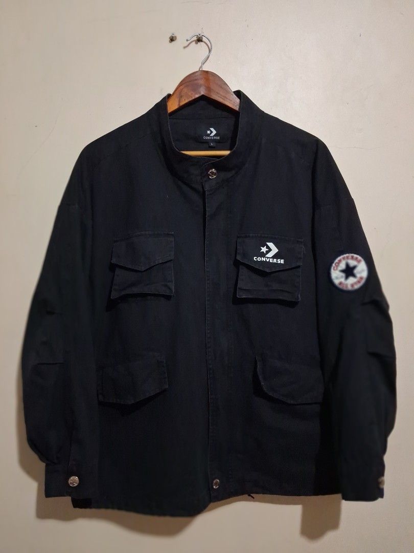Converse Black Utility Jacket with Patches (Category: Coats, Jackets and Outerwear) located in Manila. Submitted by randf_selections (Listing ID 1464124127, Image 1). Description: Black Converse jacket. Has multiple utility pockets on the front. Features a Converse patch on the left sleeve and a circular Converse All Star patch on the upper right sleeve. Button closure. Size L..