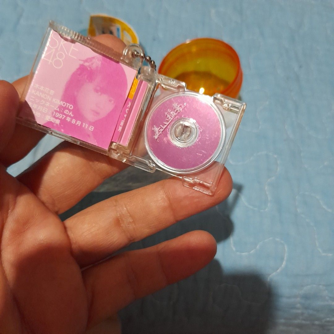 Gachapon Capsule Toy with Mini CD Keychain (Category: Designer & Blind Box Toys) located in Bocaue. Submitted by marajapansurplus (Listing ID 1464018896, Image 1). Description: - Authentic Gachapon capsule toy - Includes a mini CD with Japanese text - Features a keychain with a girl's picture - Original orange and blue capsule packaging - Sold as is.