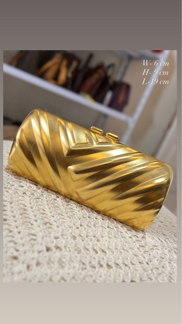 Gold Chevron Clutch Bag with Chain (Category: Luxury Bags & Wallets) located in Bacolod City. Submitted by vintage_vogue6100 (Listing ID 1464017378, Image 1). Description: - Stunning shiny gold clutch bag - Elegant chevron pattern all over - Secure clasp closure - Includes a detachable gold chain strap - Lined with soft black velvet interior - Compact size: 19cm (L) x 9cm (H) x 6cm (W).