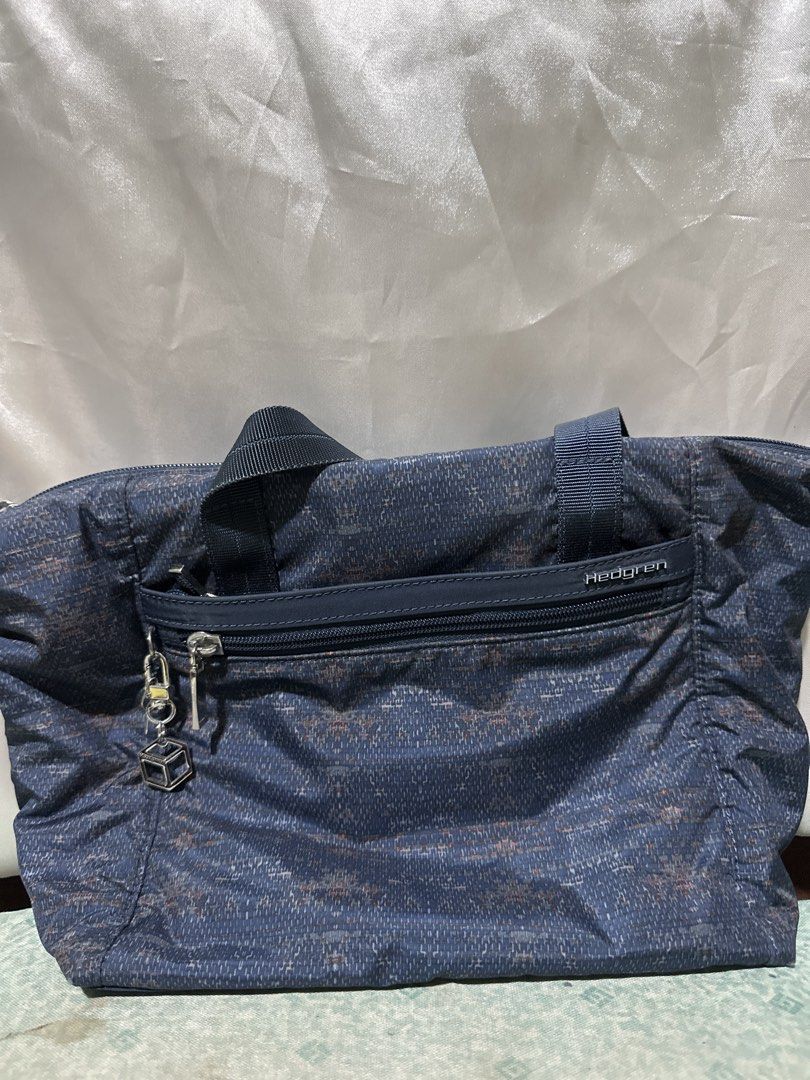 Hedgren Blue Patterned Tote Bag (Category: Tote Bags) located in Balanga. Submitted by jk2025. (Listing ID 1463954607, Image 1). Description: - Stylish blue tote bag with a subtle patterned design. - Convenient zippered front pocket adorned with a cute cube charm. - Durable dark blue webbing handles for comfortable carrying. - Ideal for everyday errands or your next travel adventure..