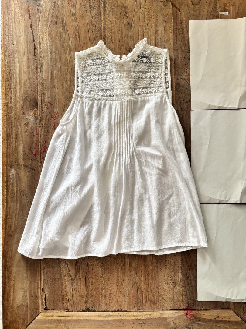 H&M White Lace Trim Sleeveless Top (Category: Sleeveless) located in Paranaque City. Submitted by ggg.bin (Listing ID 1464044939, Image 2). Description: - White sleeveless top from H&M - Features delicate lace trim on neckline and shoulders - Button-up front with gathered bodice detail - Lightweight fabric, ideal for hot weather - Versatile for casual or dressy occasions.