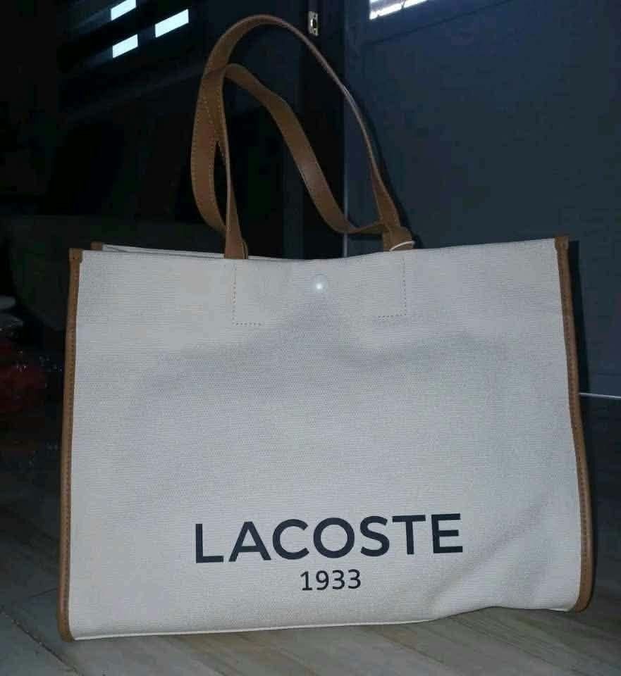 Lacoste 1933 Canvas Tote Bag (Category: Tote Bags) located in Quezon City. Submitted by elihur.tuazon (Listing ID 1464070032, Image 2). Description: - White canvas tote bag - Brown trim and handles - Large Lacoste 1933 logo on front - Brand new with original tags and packaging - Ideal for everyday use or travel.