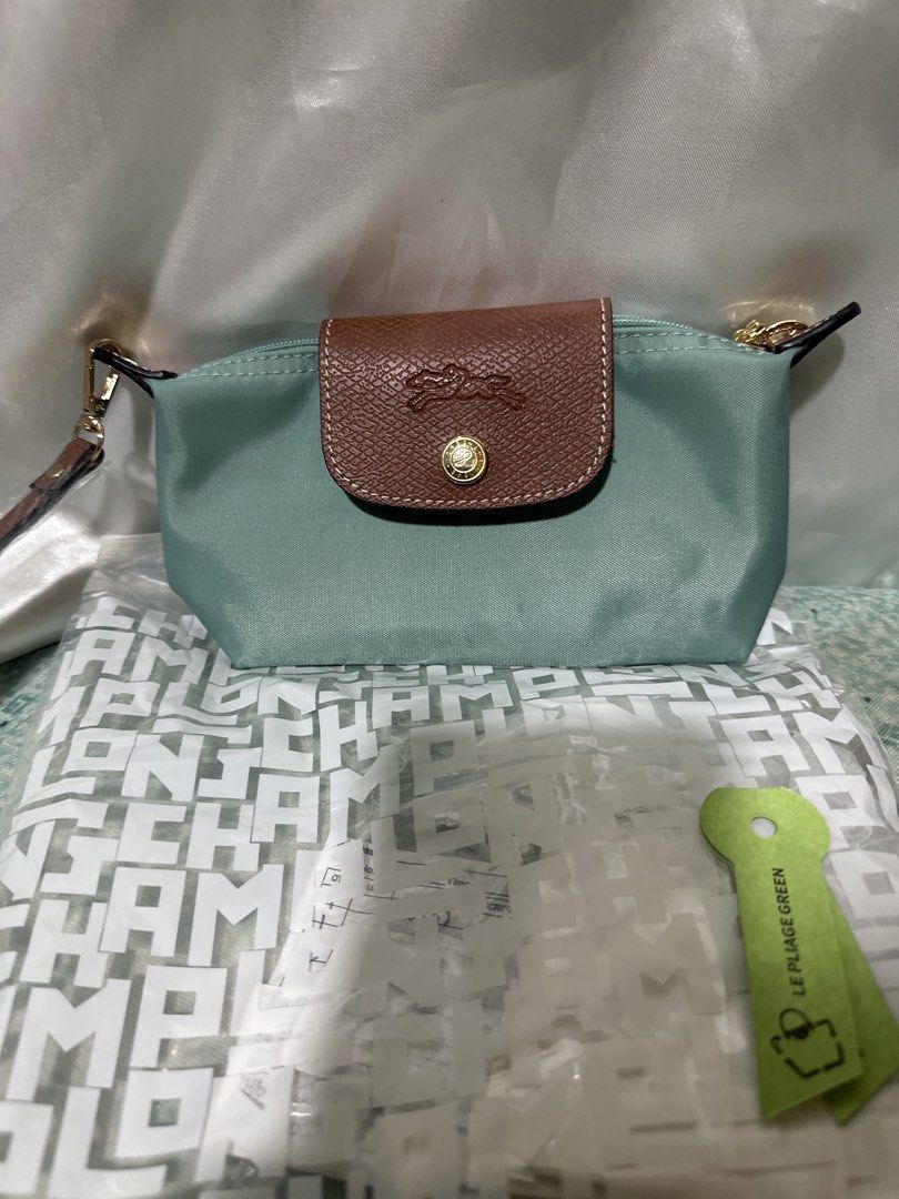 Longchamp Le Pliage Green Pouch (Category: Luxury Bags & Wallets) located in Balanga. Submitted by jk2025. (Listing ID 1463962326, Image 1). Description: - Light green pouch with brown leather trim - Features iconic Longchamp horse logo - Detachable wrist strap included - Brand new, still in original packaging with tags attached - Ideal for organizing your daily essentials.