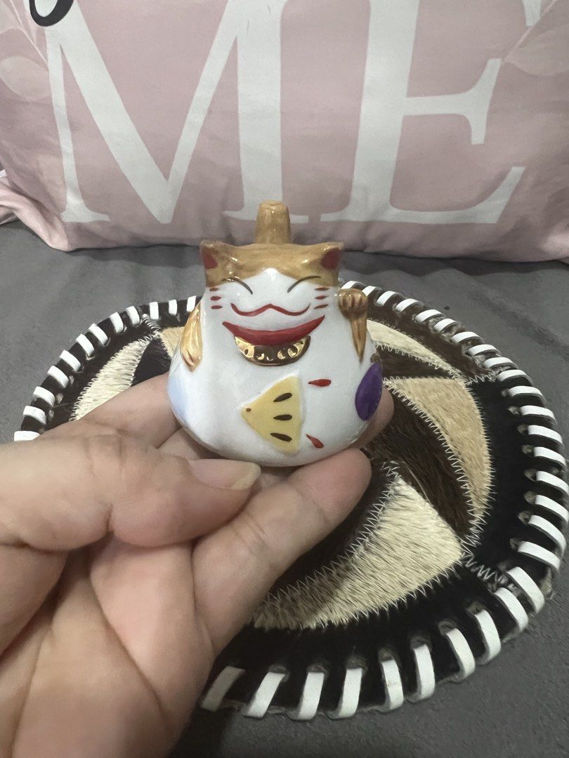 Lucky Cat Maneki Neko Figurine with Unique Coaster (Category: Vintage Collectibles) located in Las Pinas. Submitted by maple0305 (Listing ID 1464047676, Image 3). Description: - Adorable white Maneki Neko cat figurine - Waving paw to bring good luck - Features a charming gold hat and fish detail - Sits on a unique round coaster made of stitched animal fur patches - Coaster has a stylish black and white striped edge - Ideal for home decoration or 
