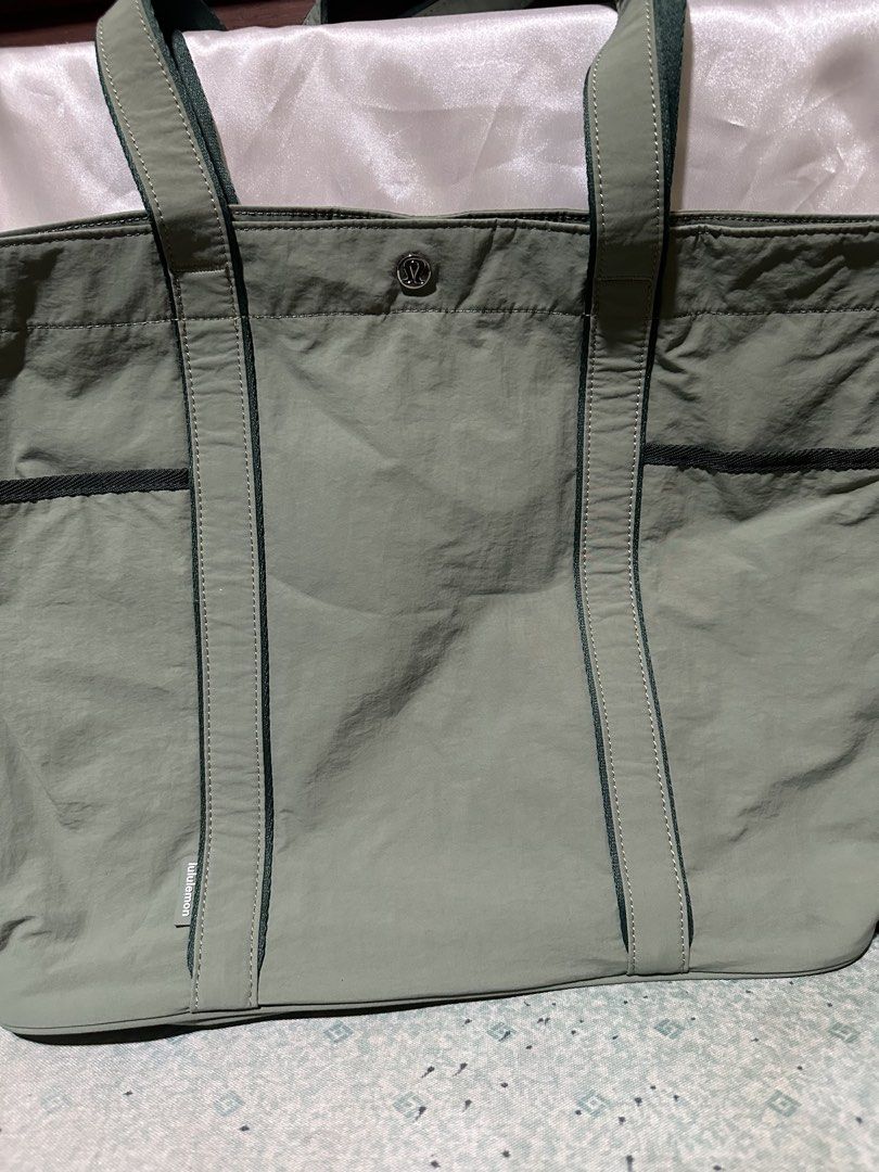 Lululemon Tote Bag (Category: Tote Bags) located in Balanga. Submitted by jk2025. (Listing ID 1463960958, Image 1). Description: - Sage green Lululemon tote bag - Features convenient exterior pockets - Visible Lululemon logo on the front - Contrasting darker green straps - Ideal for everyday errands or gym sessions.