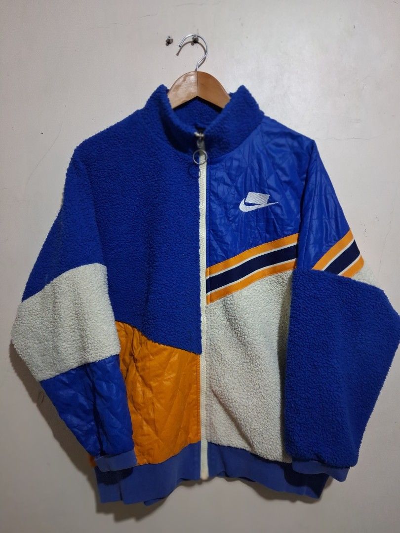Nike Colorblock Fleece and Nylon Jacket (Category: Coats, Jackets and Outerwear) located in Manila. Submitted by randf_selections (Listing ID 1464124264, Image 1). Description: Cool Nike jacket with a mix of blue fleece and blue quilted nylon. Features orange and white stripe details on the sleeves. Zipper closure. Great for staying warm and stylish. Perfect for casual wear..