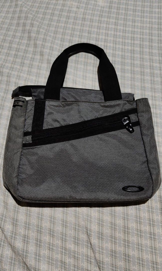 Oakley Essential Small Tote Bag (Category: Tote Bags) located in Davao. Submitted by kib_abagnalejr. (Listing ID 1464049332, Image 1). Description: Oakley Essential Small Tote featuring a distinctive diagonal front zipper and black top handles - In Pristine Condition.