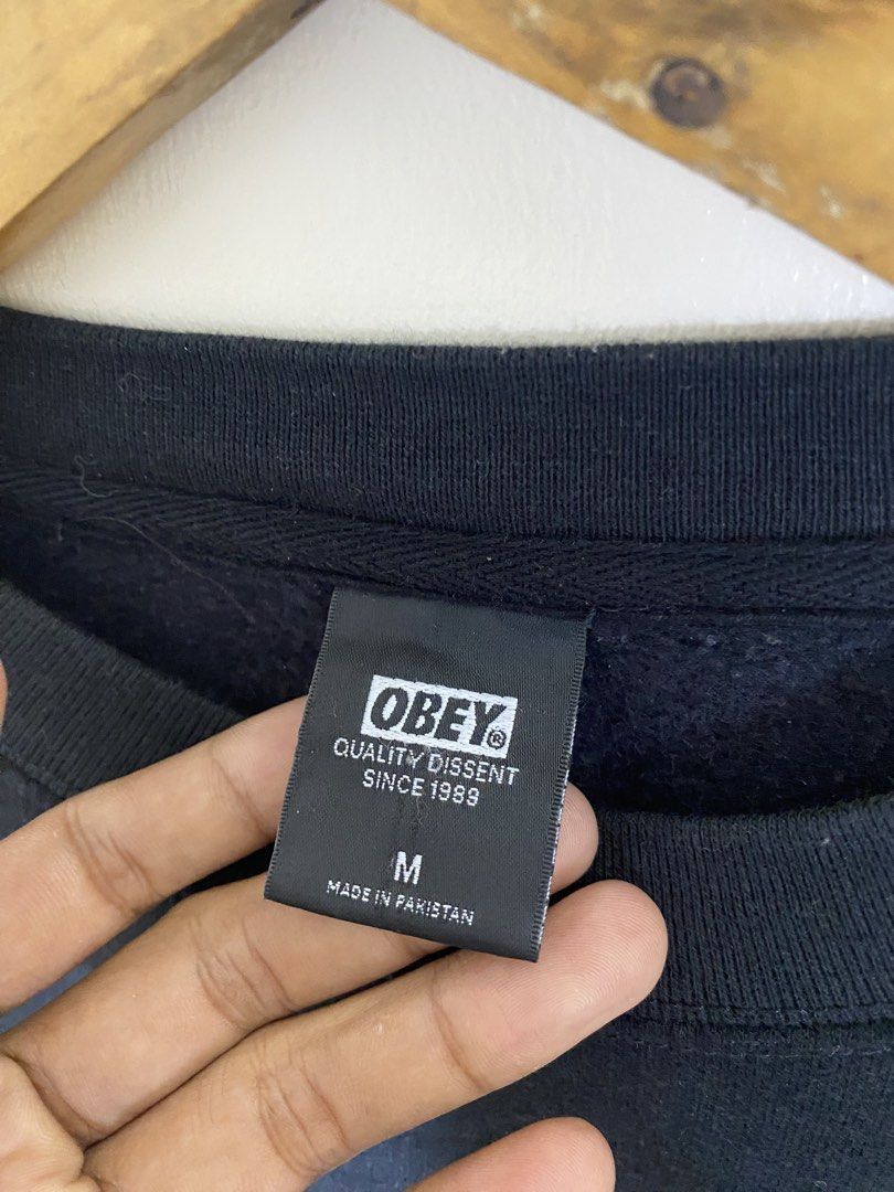 OBEY "OBEY" Logo Sweatshirt Size M (Category: Coats, Jackets and Outerwear) located in Manila. Submitted by carbertjakosalem (Listing ID 1464117912, Image 2). Description: - Brand: OBEY - Color: Black - Design: White "OBEY" logo graphic on front - Size: Medium (M) - Material: 80% Cotton, 20% Polyester - Origin: Made in Pakistan - Condition: Good, suitable for casual wear - Additional: Please check photos for detailed condition..