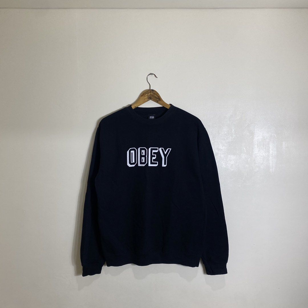 OBEY "OBEY" Logo Sweatshirt Size M (Category: Coats, Jackets and Outerwear) located in Cebu City. Submitted by theloose.thread (Listing ID 1464119222, Image 1). Description: - Brand: OBEY - Color: Black - Design: White "OBEY" logo graphic on front - Size: Medium (M) - Material: 80% Cotton, 20% Polyester - Origin: Made in Pakistan - Condition: Good, suitable for casual wear - Additional: Please check photos for detailed condition..