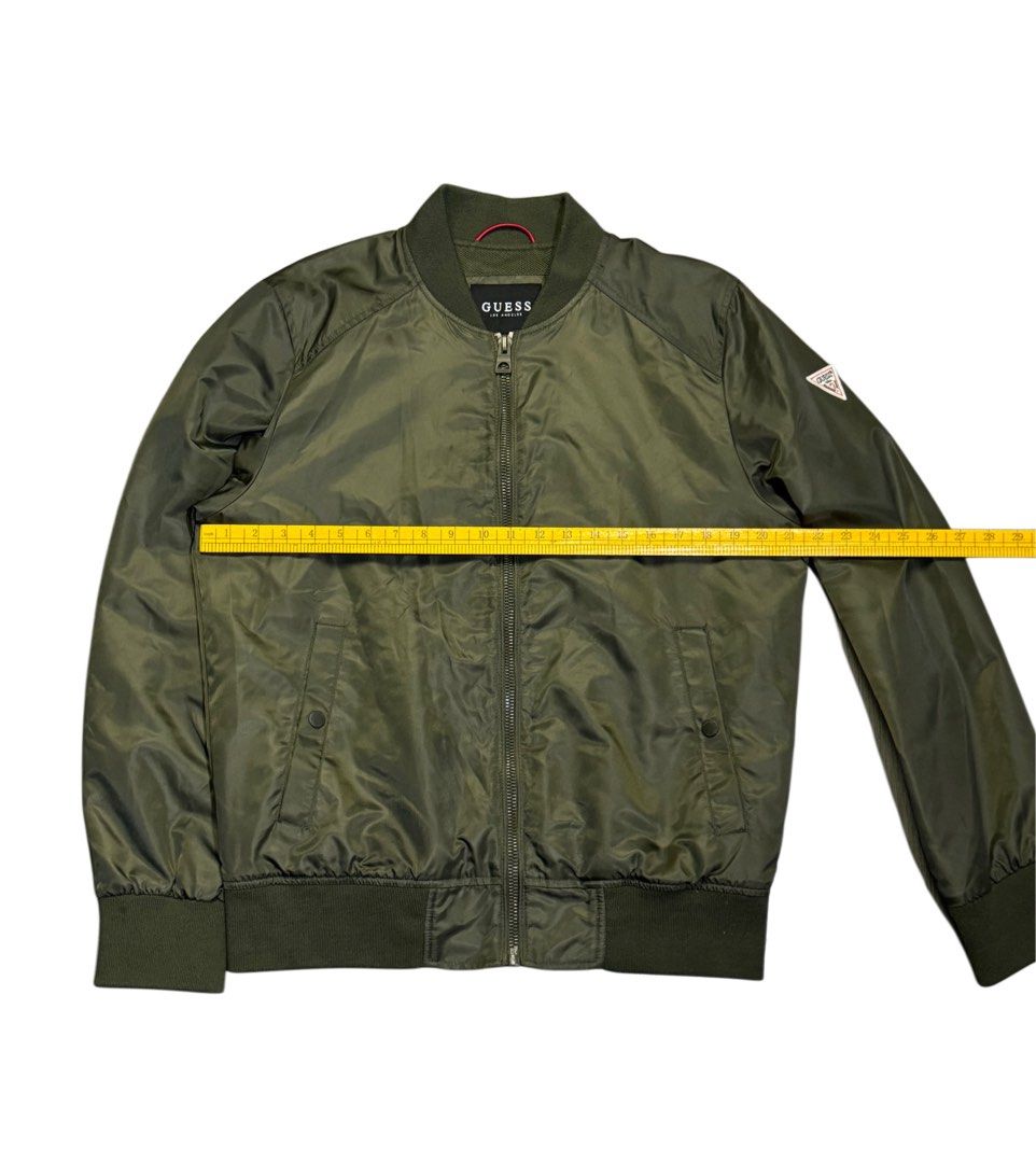 Olive Green GUESS Bomber Jacket (Category: Coats, Jackets and Outerwear) located in Caloocan City. Submitted by mzcollection_349 (Listing ID 1463961825, Image 3). Description: - Olive green GUESS bomber jacket - Classic MA-1 style - Zip-up front with two side pockets - Ribbed cuffs and hem for a snug fit - Vibrant red interior lining - Ideal for versatile layering.