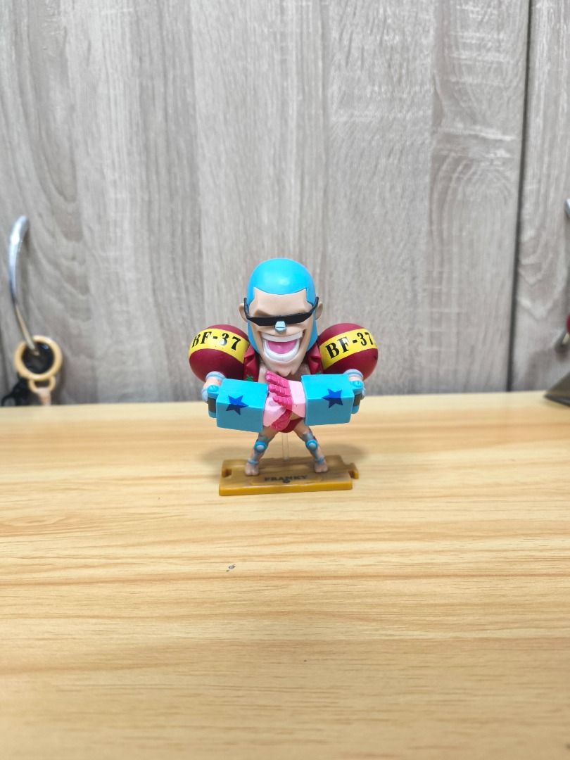 Franky Figure - One Piece (Category: Figurines & Statues) located in Santa Rosa. Submitted by tinytoycrate (Listing ID 1464103732, Image 1). Description: - Collectible Franky figure from the popular anime One Piece. - Compact size, ideal for display or gifting to fans. - Comes with a yellow base clearly labeled 'FRANKY'. - Franky is depicted holding a unique pink and blue object with star details. - Features 'BF-37' marking on the character's arm