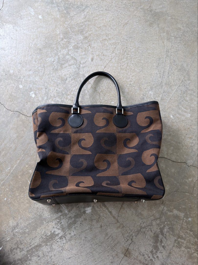 Pierre Cardin Canvas Tote Bag (Category: Tote Bags) located in Alfonso. Submitted by jbcamet (Listing ID 1464023352, Image 1). Description: - Authentic Pierre Cardin tote bag - Unique brown and black patterned exterior - Genuine leather trim and handles - Protective metal studs on the bottom - Secure snap closure - Spacious main compartment - Interior zippered pockets for organization - Ideal for everyday use.