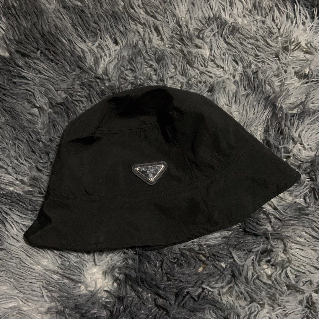 Prada Black Nylon Bucket Hat (Category: Caps & Hats) located in Compostela. Submitted by anyastark (Listing ID 1464126183, Image 1). Description: - Prada bucket hat - Black nylon material - Iconic Prada triangle logo on the front - Perfect for sunny days or stylish outfits - Simple and classic design.