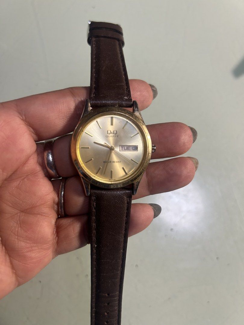 Q&Q Quartz Watch with Leather Strap (Category: Men's Watches) located in Cavite. Submitted by mamamia73 (Listing ID 1464036996, Image 1). Description: - Gold-tone analog watch - Displays day and date - Water resistant - Brown leather strap (shows some wear) - Works well - Ideal for everyday wear.
