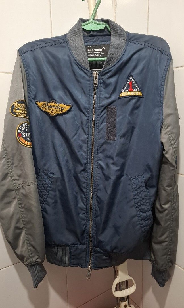 SUPERDRY Bomber Jacket (Category: Coats, Jackets and Outerwear) located in Manila. Submitted by gentleclosetcollection (Listing ID 1464058704, Image 1). Description: *Brand: Superdry *​Model / Line: Superdry Issue 23rd Squadron "Lightning" Flight Bomber Jacket *​Style Code: M50801TNS (Code: 133090) *​Tag Size: Small (S) (Fits true to size / slim fit) *Color: Navy Blue & Slate Grey *​Features: Full front zip, patches, side pockets, ribbed hem and 