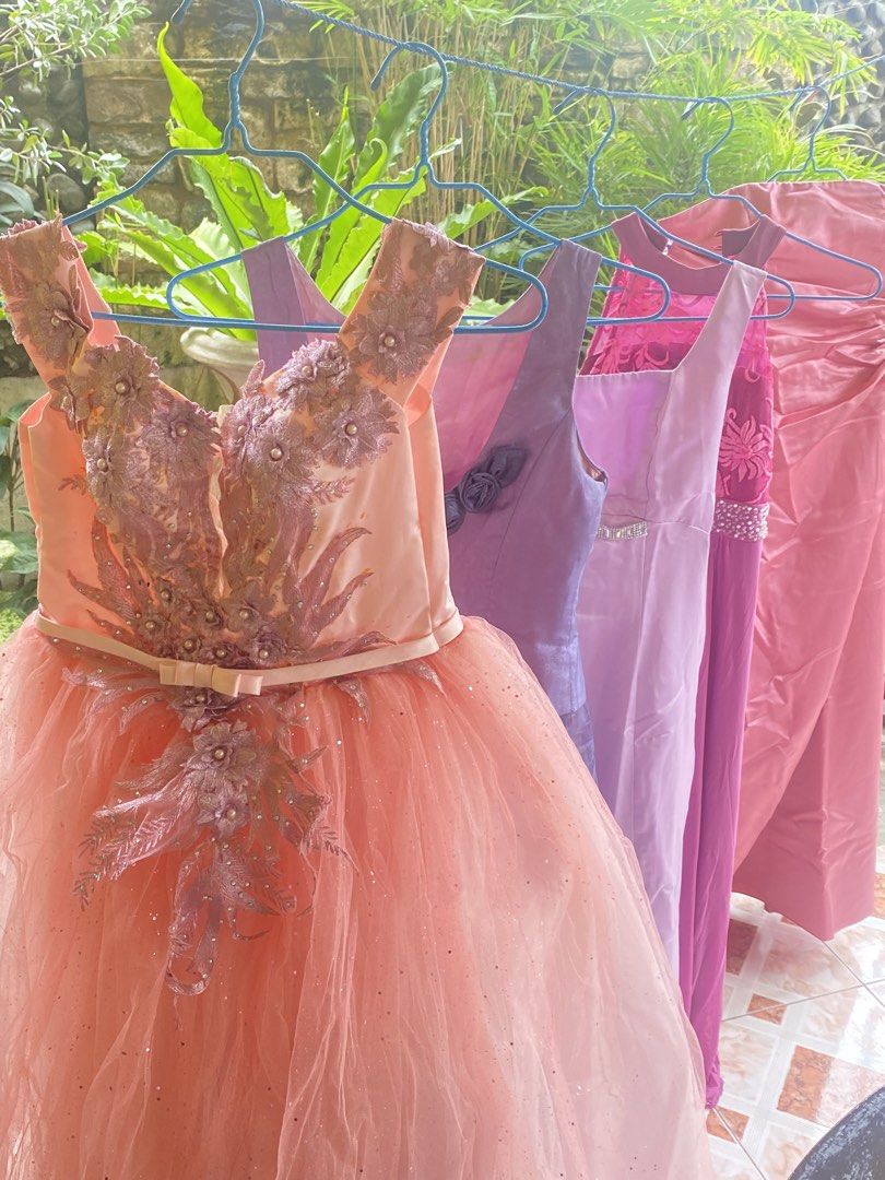 TAKE ALL 7 Assorted Gowns - Pink, Purple, Lavender (Category: Dresses) located in Davao. Submitted by alessuh (Listing ID 1463965646, Image 2). Description: - Stunning collection of formal dresses perfect for any event or party. - Includes a beautiful peach tulle gown with intricate beadwork. - Elegant purple satin gown available. - Lovely lavender and pink dresses adorned with embellishments and floral accents. - All pieces are unique and crafte