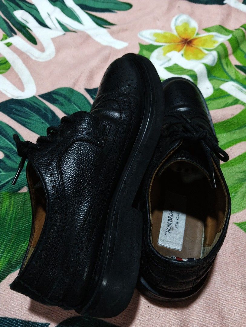 Thom Browne Black Leather Wingtip Brogues (Category: Dress Shoes) located in Davao. Submitted by noelamihan05424 (Listing ID 1464052940, Image 3). Description: - Brand: Thom Browne - Color: Black - Style: Wingtip Brogues - Material: Leather - Features: Classic brogue detailing with perforations, lace-up front - Signature Detail: Red, white, and blue stripe on heel tab - Versatility: Perfect for dressing up or down - Size 39 on tag - Actual size 4