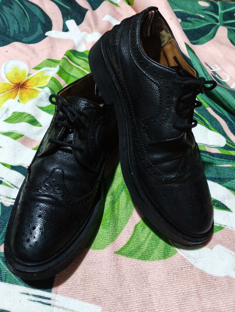 Thom Browne Black Leather Wingtip Brogues (Category: Dress Shoes) located in Davao. Submitted by noelamihan05424 (Listing ID 1464052940, Image 2). Description: - Brand: Thom Browne - Color: Black - Style: Wingtip Brogues - Material: Leather - Features: Classic brogue detailing with perforations, lace-up front - Signature Detail: Red, white, and blue stripe on heel tab - Versatility: Perfect for dressing up or down - Size 39 on tag - Actual size 4