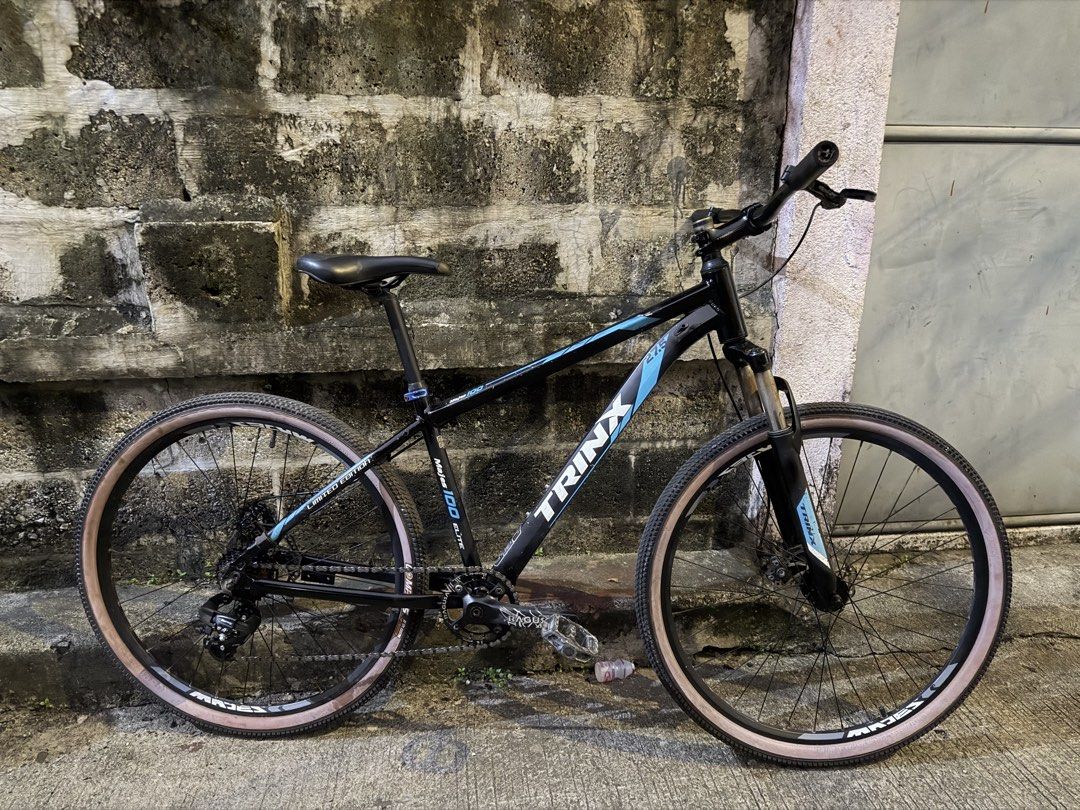 TRINX Majes 100 Elite Mountain Bike (Category: Bicycles) located in Manila. Submitted by muchoc06 (Listing ID 1464036892, Image 3). Description: - TRINX Majes 100 Elite Mountain Bike - Color: Black frame with blue accents - Features: Disc brakes (front & rear), Shimano Tourney derailleur - Tires: Light tan sidewalls - Condition: Ready for trails or city riding.
