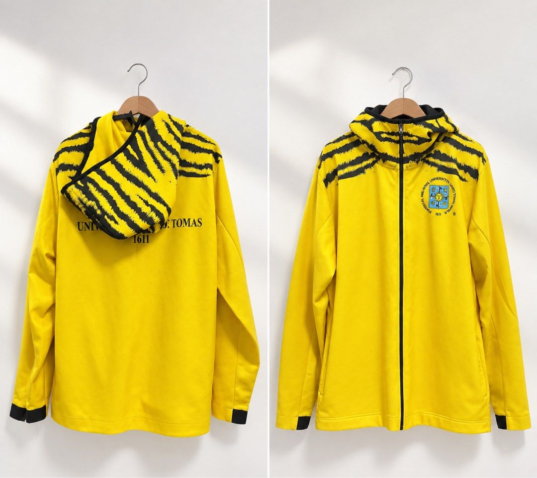 UST Official Merch Batch 2022 Varsity Jacket (Category: Coats, Jackets and Outerwear) located in Caloocan City. Submitted by shibowhii (Listing ID 1464055608, Image 1). Description: - Yellow zip-up jacket UST OFFICIAL MERCH - Features distinctive tiger stripe details on the hood and shoulders. - Showcases the official UST logo on the front. - 'University of Sto. Tomas 1611' is printed on the back. - Ideal for any proud Thomasian! - Used few times