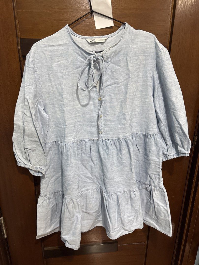 ZARA Light Blue Tiered Denim-look Top (Category: Sleeveless) located in Mandaluyong City. Submitted by clothescarousel (Listing ID 1464055330, Image 1). Description: - Light blue Zara top - Resembles denim but is a lighter fabric - Features a stylish tie-neck detail - Tiered and flowy design for a relaxed silhouette - Three-quarter sleeves with a subtle puff - Ideal for casual wear.
