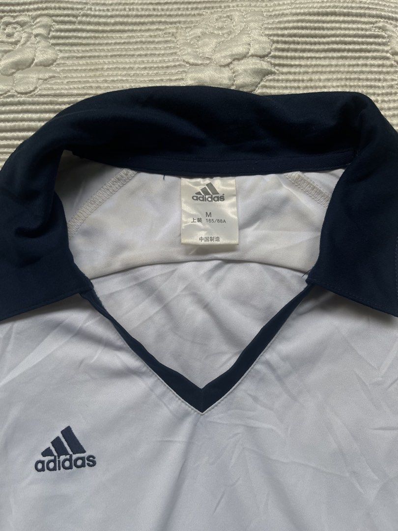 Adidas White Navy Blue Soccer Jersey Size M (Category: Activewear) located in Alabel. Submitted by geragarhea13830 (Listing ID 1464297321, Image 2). Description: - White Adidas jersey - Navy blue accents - Classic Adidas logo on chest - V-neck collar - Size: Medium (M) - Made in China - Ideal for sports or casual wear.