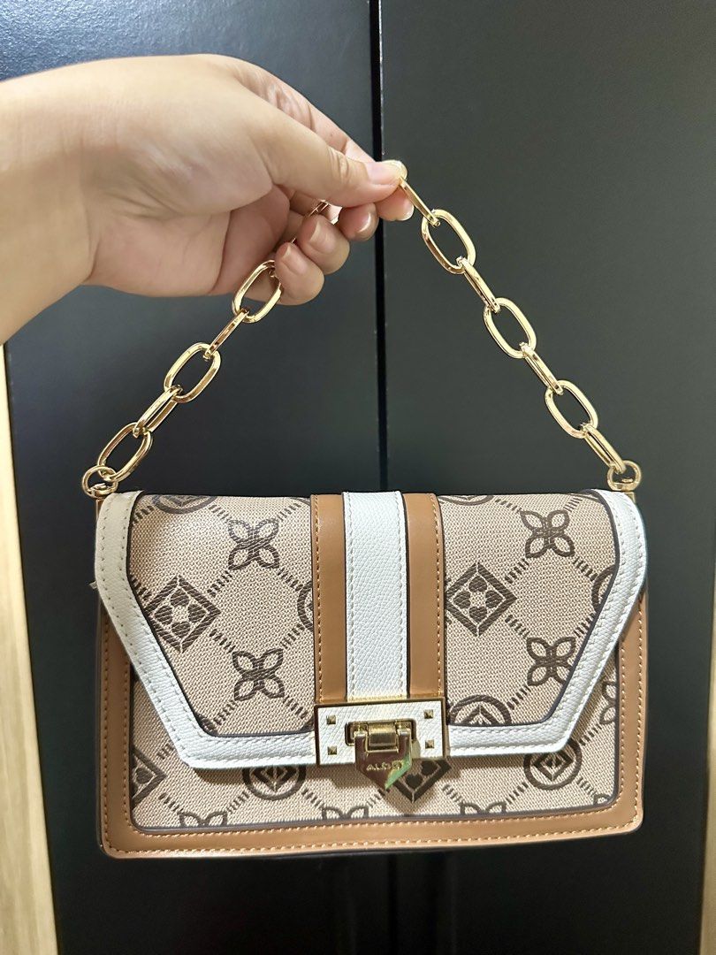 ALDO Monogram Chain Shoulder Bag (Category: Shoulder Bags) located in Manila. Submitted by biskybysh (Listing ID 1464346742, Image 1). Description: - Cute ALDO bag with signature monogram print - Colorway: Tan, white, and brown - Gold chain strap - Clasp closure - Interior still wrapped in plastic - Great for going out.