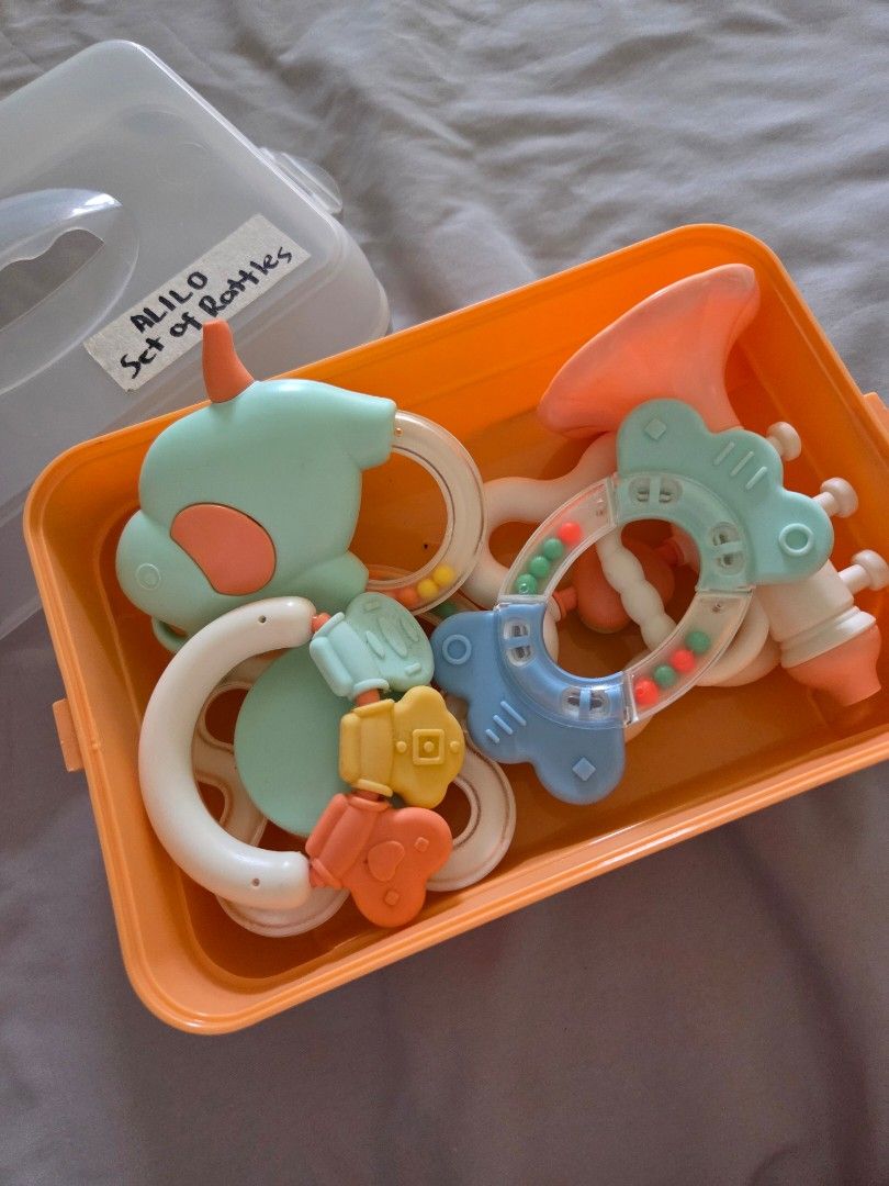ALILO Set of Rattles for Babies (Category: Kids Toys) located in Taguig. Submitted by bbbautista (Listing ID 1464200450, Image 1). Description: Set of baby rattles in a clear storage case. Includes various shapes and colors like a giraffe, elephant, and heart. Great for sensory development and teething. All pieces are in the orange container. Some rattles have beads inside for sound. Perfect for little ones. Rfs decluttering baby toys Pick up in 