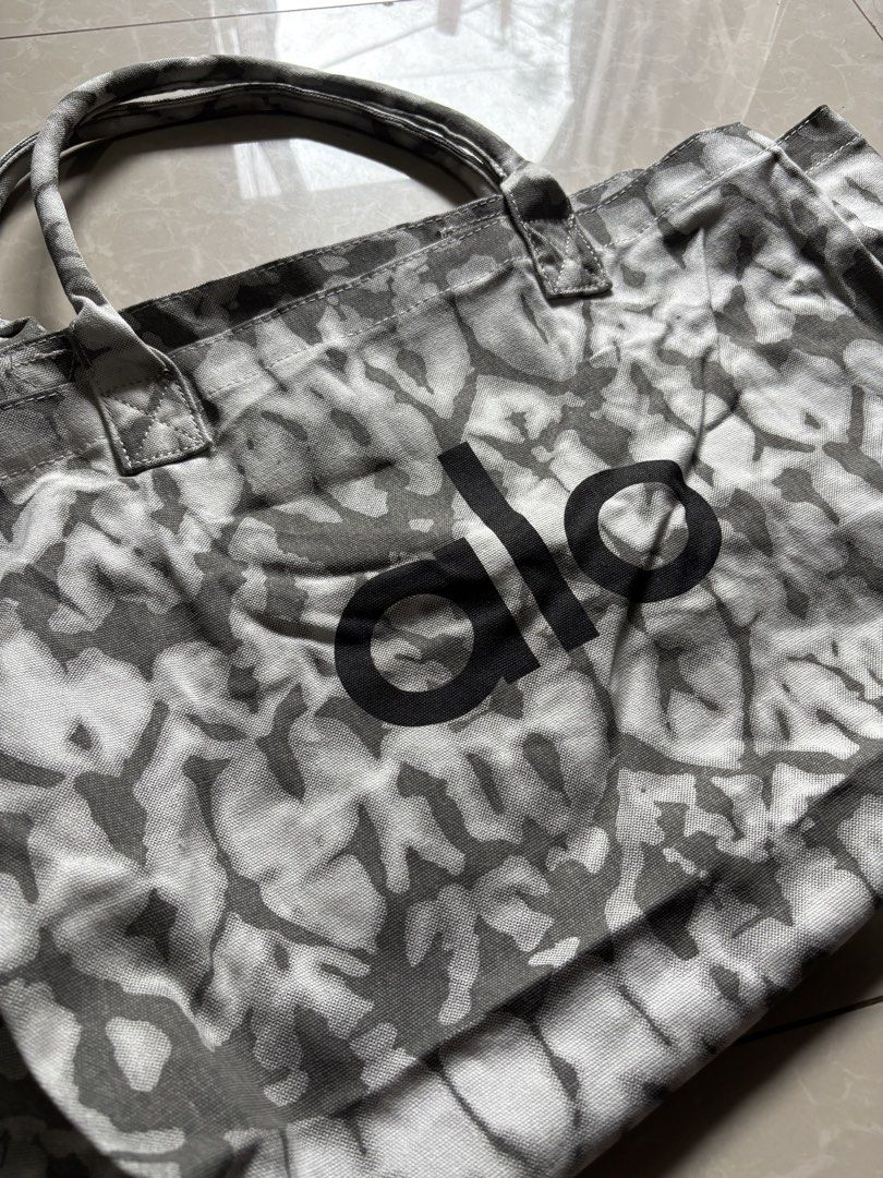 Alo Tote Bag Tie-Dye Print (Category: Tote Bags) located in Quezon City. Submitted by nojthrift (Listing ID 1464252530, Image 2). Description: - Stylish tie-dye print Alo tote bag - Features a black 'alo' logo on the front - Durable canvas material - One size fits all - Ideal for everyday use, gym sessions, or beach outings - Offers ample interior space.
