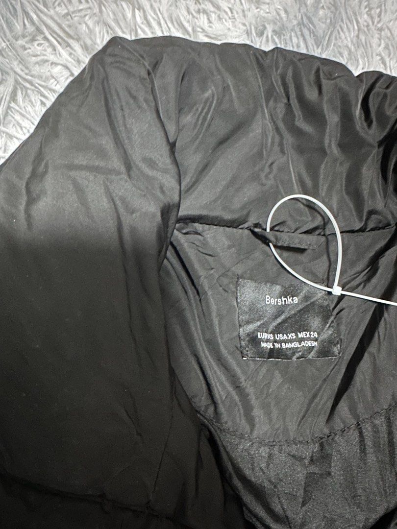 Bershka Black Puffer Jacket (Category: Coats, Jackets and Outerwear) located in Batangas. Submitted by kulilayfinds (Listing ID 1464279571, Image 3). Description: - Brand: Bershka - Type: Black Puffer Jacket - Size: XS - Closure: Zip-up front with ring pull - Features: Adjustable drawstrings at hem, two side pockets with snap button closure - Origin: Made in Bangladesh Flaw - the drawstrings show signs of wear.